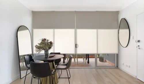 Dual roller blinds on wide sliding door to a balcony in a dining room with a small round black table and 4 black chairs