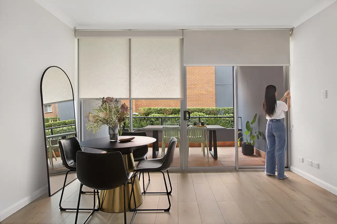 Woman adjusting a roller blind on a sliding glass door in a modern Australian dining room