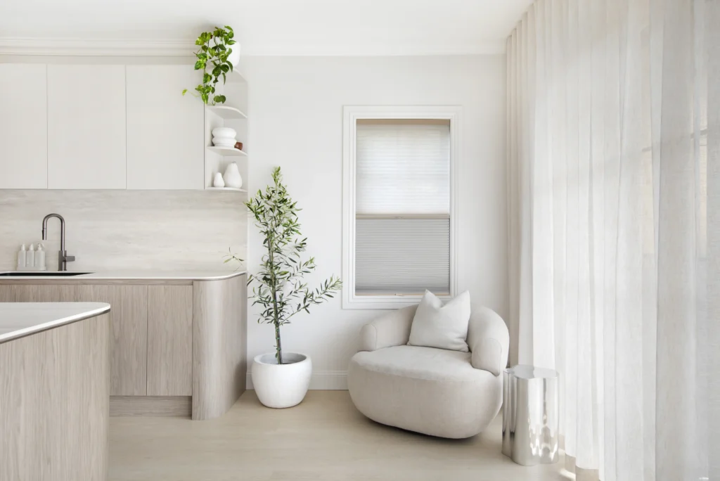 honeycomb blind and sheer curtains in light-filled Sydney kitchen nook with timber cabinetry and round armchair