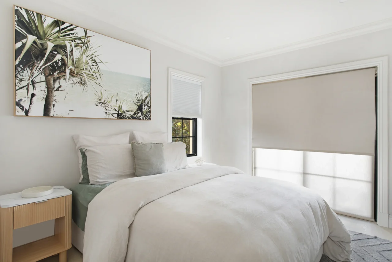 blockout and translucent roller blinds on bedroom windows in light Sydney bedroom with coastal artwork