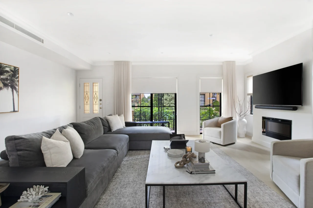 linked roller blinds and linen curtain panels on balcony doors in heritage Sydney living room with charcoal sofa and fireplace